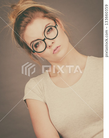 Bored focused teenage woman wearing eyeglasses 133660359