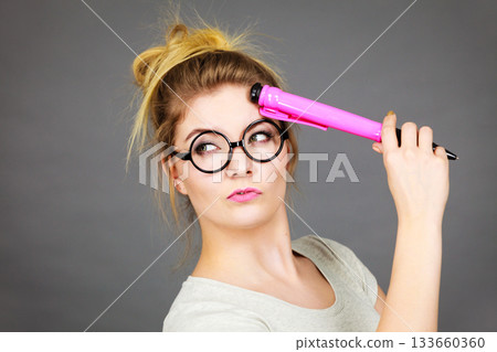 Woman holding big oversized pencil thinking about something 133660360