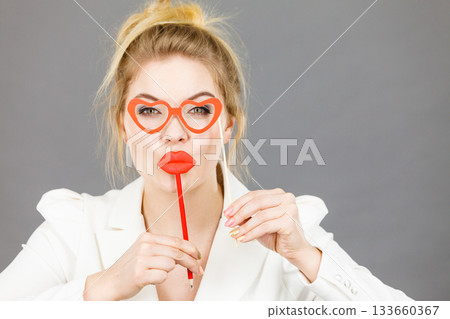 Happy elegant woman holding carnival accessoies on stick Happy elegant woman holding carnival accessoies on stick 133660367