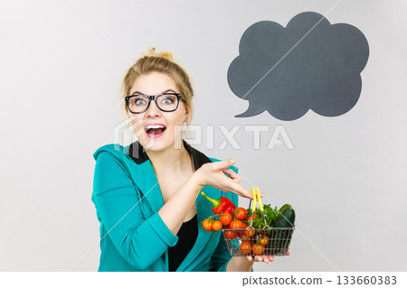 Woman holds shopping cart with vegetables, copy space Woman holds shopping cart with vegetables, copy space 133660383