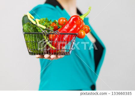 Woman hand holds shopping basket with vegetables Woman hand holds shopping basket with vegetables 133660385