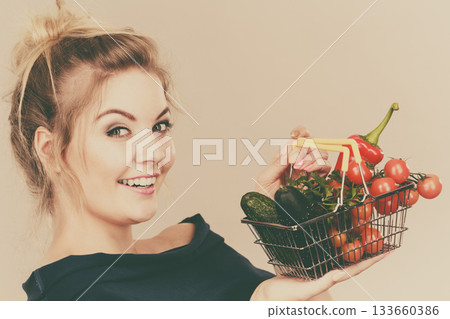Woman holds shopping basket with vegetables Woman holds shopping basket with vegetables 133660386
