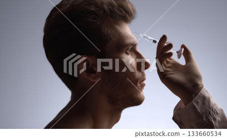 Specialist preparing forehead filler injection to soften expression lines Specialist preparing forehead filler injection to soften expression lines 133660534