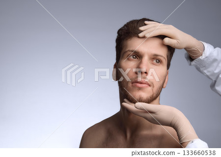 Aesthetic specialist reviewing male forehead and jaw alignment. 133660538