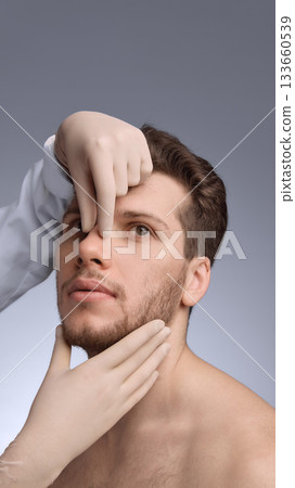 Doctor examining male nose structure during facial assessment. 133660539