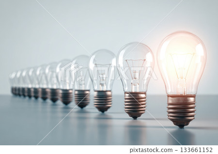 One glowing lightbulb stands out among row of transparent lightbulbs, symbolizing creativity, innovation, and individuality in minimalist, modern setting 133661152