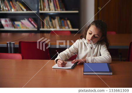 Young Girl Studying At Library Table With Notebook And Books In School Setting Young Girl Studying At Library Table With Notebook And Books In School Setting 133661309