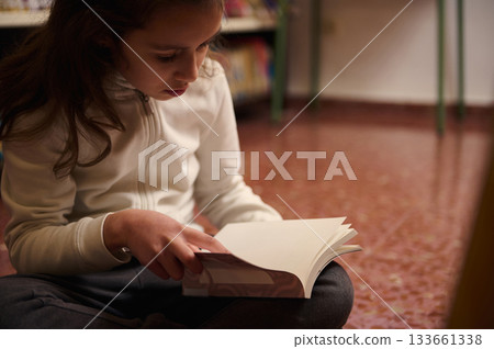 Young Girl Reading a Book in a Library During Quiet Study Moment, Focused Learning 133661338