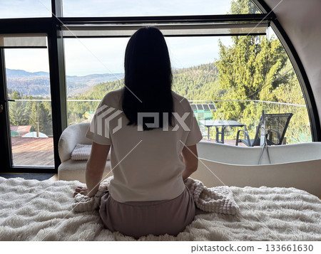 Calm adult woman sitting on bed in relaxed morning atmosphere, peaceful home routine, comfort and wellness lifestyle concept 133661630