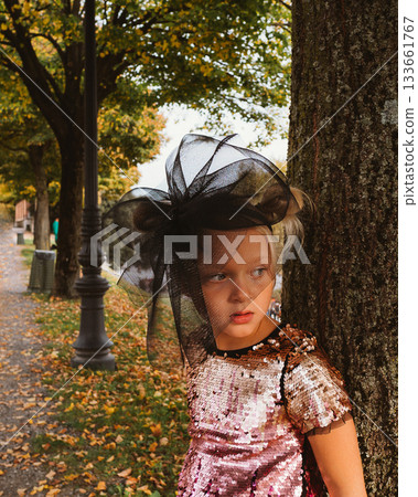 Child in Sequin Dress and Hat Posing by Tree 133661767