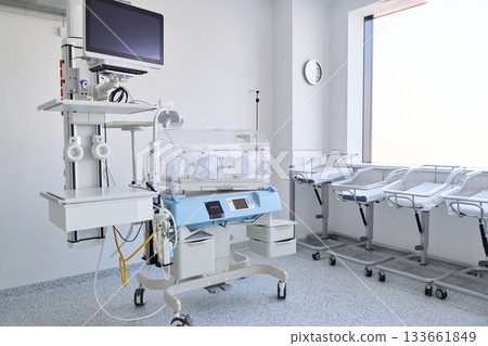 Medical equipment setup in a neonatal care unit with incubators and monitors in a bright hospital room Medical equipment setup in a neonatal care unit with incubators and monitors in a bright hospital room 133661849