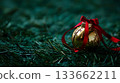 A gold ornament with a red ribbon sits on a green field 133662211