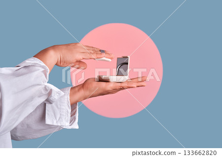 Hands applying face powder from compact case 133662820