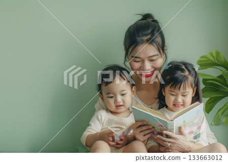 Mom with little kids reading, highlighting gentle care and shared time in a family home. 133663012