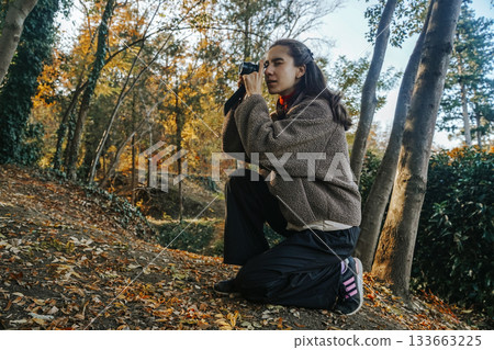 Young Woman Engaging in Photography in Sunny Autumn Forest Young Woman Engaging in Photography in Sunny Autumn Forest 133663225