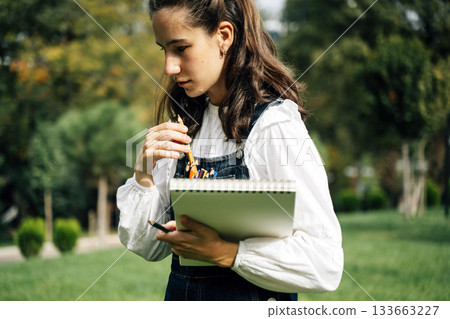 Girl Drawing in Summer Park. Relax lifestyle portrait Girl Drawing in Summer Park. Relax lifestyle portrait 133663227