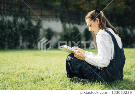 Girl Drawing in Summer Park. Relax lifestyle portrait Girl Drawing in Summer Park. Relax lifestyle portrait 133663229