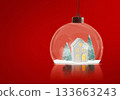 A glass snow globe with a small white house and two green trees inside. 133663243