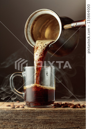 Black coffee is poured in a clear glass mug. Black coffee is poured in a clear glass mug. 133664000