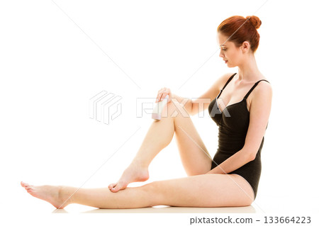 Woman shaving her legs with electric razor 133664223
