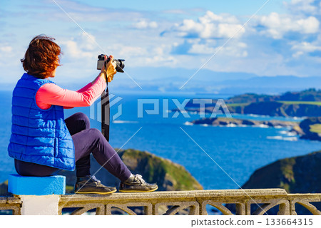 Tourist with camera on Asturias coast, Spain 133664315