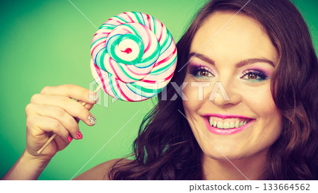 Smiling girl with lollipop candy on green 133664562