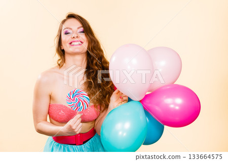 Woman holds lollipop candy and balloons Woman holds lollipop candy and balloons 133664575