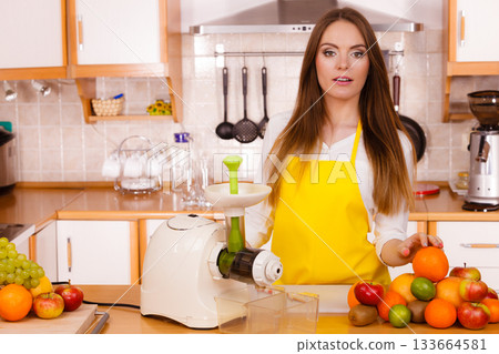 Woman in kitchen preparing fruits for juicing 133664581