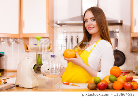 Woman in kitchen preparing fruits for juicing 133664582