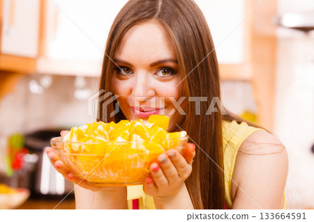 Woman holds bowl full of sliced orange fruits 133664591
