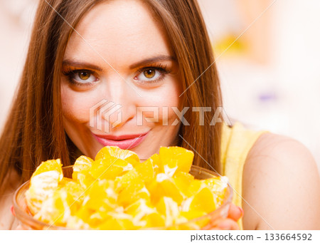 Woman holds bowl full of sliced orange fruits 133664592