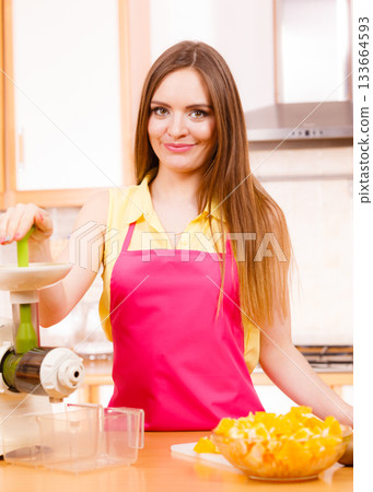 Woman making orange juice in juicer machine 133664593
