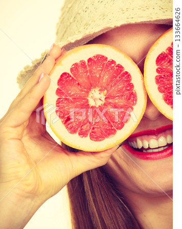 Woman holds two halfs of grapefruit citrus fruit in hands 133664626