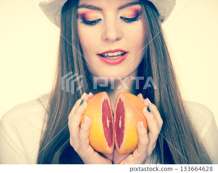 Woman holds two halfs of grapefruit citrus fruit in hands 133664628