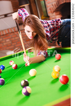 Young woman playing billiard. Young woman playing billiard. 133664642