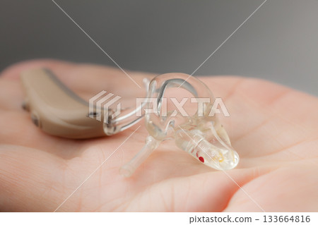 senior person holding hearing aid closeup 133664816