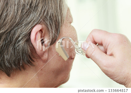 Closeup senior woman using hearing aid 133664817