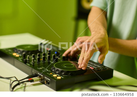 DJ setup overview, Energetic club DJ performing with digital controller in action, Content creator mixing music live using digital turntables under vibrant stage lights 133664958