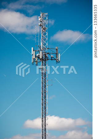 Tall cellular communication tower with antennas and radio equipment against bright blue sky Tall cellular communication tower with antennas and radio equipment against bright blue sky 133665335