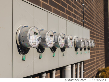 Row of smart electric meters on building exterior for multi-unit energy monitoring Row of smart electric meters on building exterior for multi-unit energy monitoring 133665341