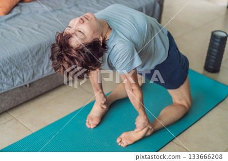 Elderly woman practicing yoga in her cozy living room, stretching on a mat and maintaining balance. Concept of healthy aging, active senior lifestyle, mindfulness, wellness, and daily home exercise Elderly woman practicing yoga in her cozy living room, stretching on a mat and maintaining balance. Concept of healthy aging, active senior lifestyle, mindfulness, wellness, and daily home exercise 133666208