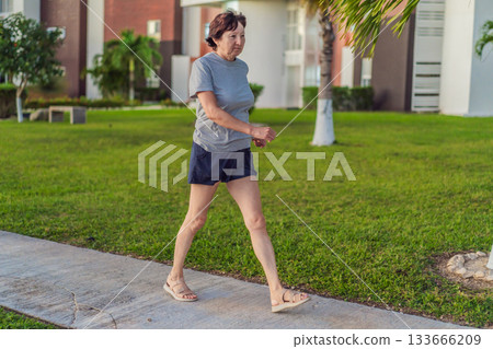 Elderly woman exercising on a grassy lawn, staying active, strong, and healthy outdoors. Concept of active aging, wellness, fitness, mobility, positive lifestyle, and healthy senior living Elderly woman exercising on a grassy lawn, staying active, strong, and healthy outdoors. Concept of active aging, wellness, fitness, mobility, positive lifestyle, and healthy senior living 133666209