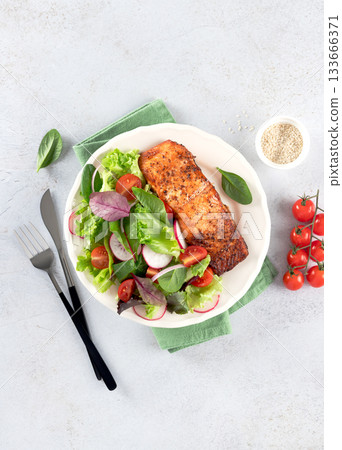 Grilled salmon fillet with fresh green salad, tomatoes, radish on white background. Healthy balanced lunch. Grilled salmon fillet with fresh green salad, tomatoes, radish on white background. Healthy balanced lunch. 133666371