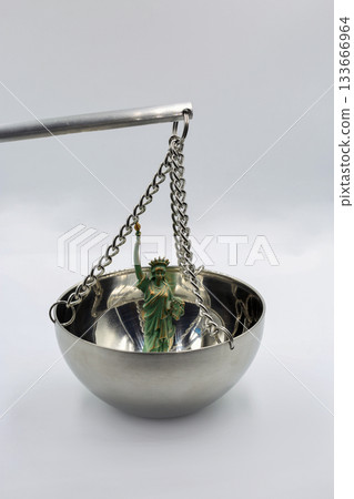 Statue of Liberty figurine on metal balance scale closeup. Statue of Liberty figurine on metal balance scale closeup. 133666964