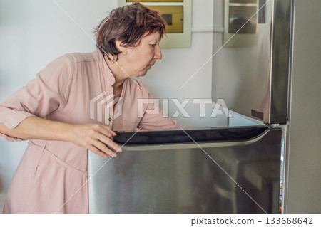 Elderly woman cooking in the kitchen, preparing a homemade meal with care and joy. Concept of healthy aging, independence, domestic life, culinary routine, and active senior lifestyle at home 133668642