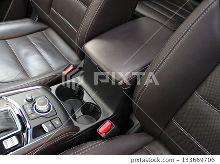 Two round cup holders near the armrest between the seats with expensive leather trim. Comfort and convenience for long travel in a premium car Two round cup holders near the armrest between the seats with expensive leather trim. Comfort and convenience for long travel in a premium car 133669706