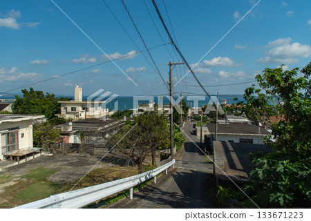 A clear sky, a cityscape with an emerald green sea, and a downhill slope 133671223