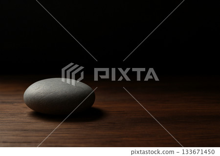 Smooth grey stone on a dark wooden table 133671450