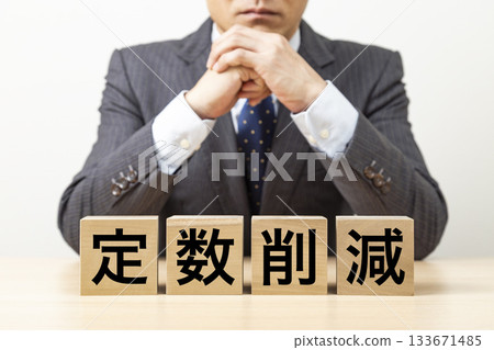 A block with the word "reduction" written on it and a businessman 133671485
