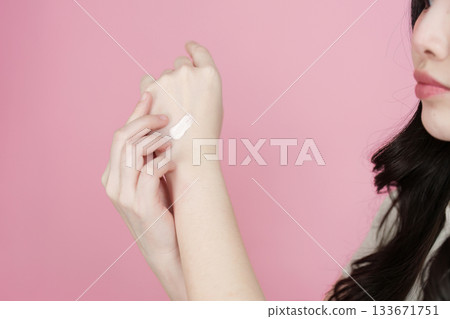 Skincare application. Young woman testing cream on her wrist. Skincare application. Young woman testing cream on her wrist. 133671751